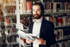 Man in a library. Guy in a black suit. Student with a books.
